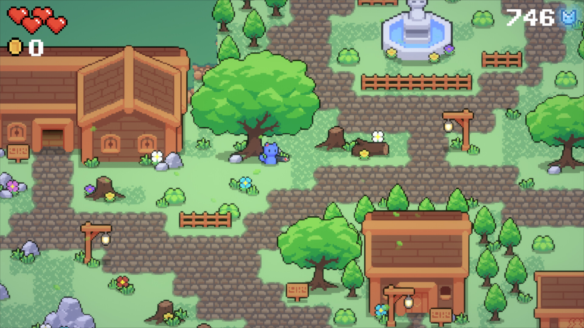 The image depicts a colorful, pixel-art style video game village scene with cobblestone pathways winding through grassy areas dotted with trees, flowers, rocks, and wooden fences. Two brown wooden houses with orange roofs are visible, along with lampposts emitting light near the pathways. Near the center of the image, a small blue character with cat-like ears is standing next to a large leafy tree. In the upper right corner, there is a stone fountain surrounded by flowers. The top left corner shows a game interface with three red heart icons and a coin count of zero, while the top right corner displays a score of 746.