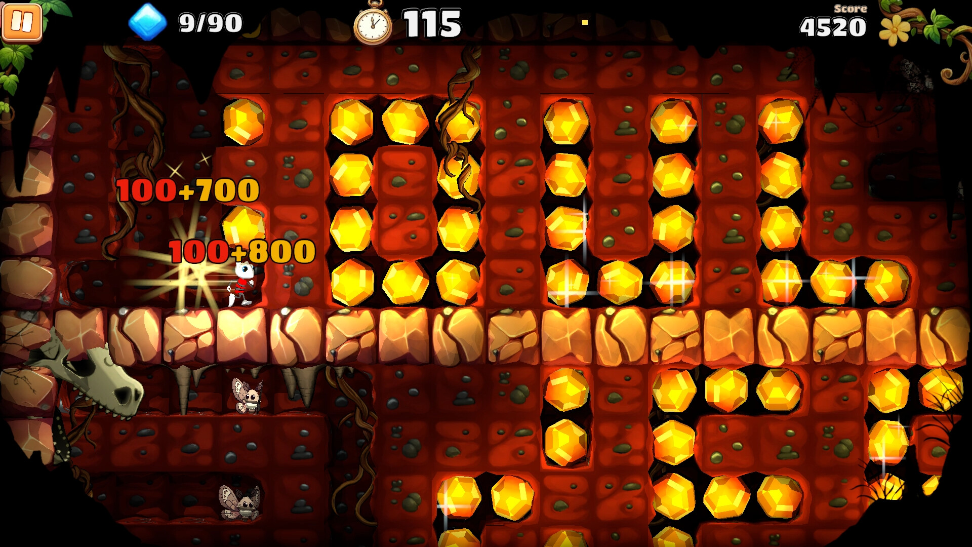 The image shows a colorful video game scene set in an underground cave with reddish-brown rocky walls and large, shiny yellow gems embedded throughout. A small character dressed in red is standing next to some glowing points where numerical scores like "100+700" and "100+800" appear, indicating points being earned. At the top of the screen, there is a timer counting down from 115, a blue gem counter showing 9 out of 90 collected, and a score of 4520 displayed on the right. The cave also features some twisted vines and skeletal remains embedded in the rocks, with small bat-like creatures occupying lower ledges, adding to the subterranean atmosphere.