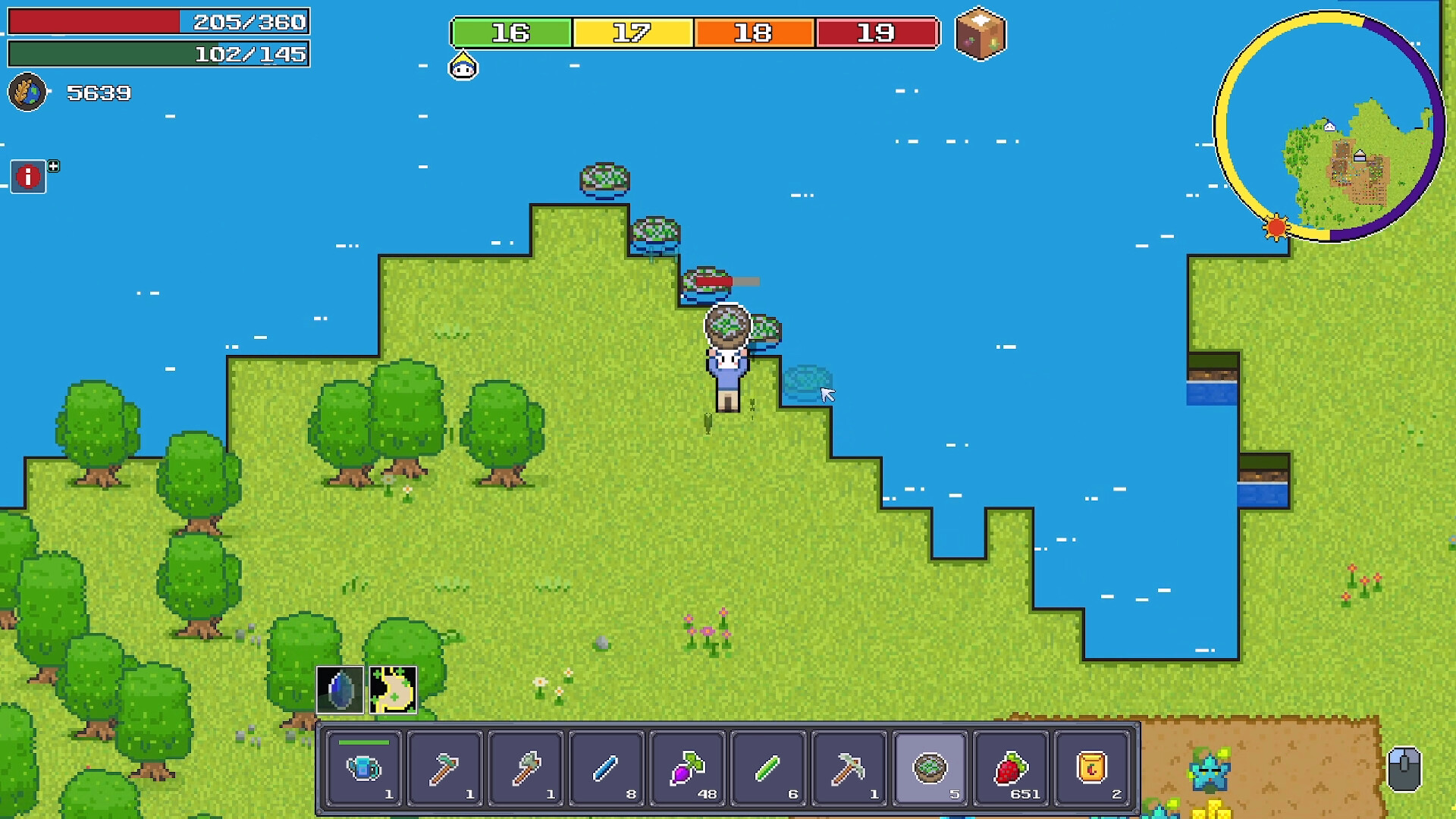The image shows a top-down view of a pixel-art style video game scene featuring a character standing on a grassy area next to a body of blue water. The character is holding a net and appears to be interacting with several small, round creatures or objects floating near the water’s edge. Surrounding the character are various trees scattered across the green terrain, with a small patch of flowers visible nearby. The game interface displays health and stamina bars at the top left, a numeric counter, and a colorful progress bar, as well as a circular mini-map showing terrain and structures in the top right corner. Along the bottom of the screen is an inventory bar containing various items such as tools, berries, and other resources.