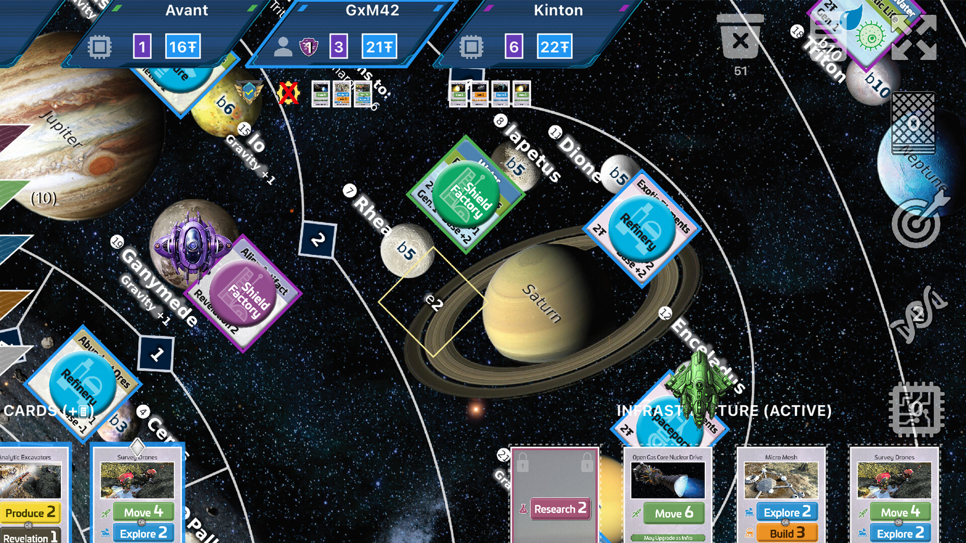 The image shows a detailed space-themed board game surface featuring planets, moons, and various game tokens and cards. The central focus is on the planet Saturn and its surrounding moons, including Rhea, Iapetus, Dione, and Enceladus, each labeled with white text and small icons indicating game values. Several colored square tokens labeled “Shield Factory” and “Refinery” are placed on or near the moons, with some accompanied by small 3D spaceship models in purple and green. At the top, player information panels display names like “Avant,” “GxM42,” and “Kinton,” along with numerical values and icons. The background is a starry outer space scene, and scattered around the board are various cards showing images of technology or actions such as “Analytic Excavators,” “Survey Drones,” and “Open Gas Core Nuclear Drive,” with associated game commands like “Produce,” “Move,” “Explore,” and “Research.” The layout suggests a strategic resource management or space exploration game.