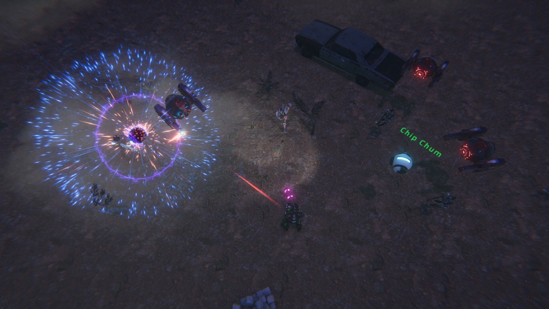 The image depicts a nighttime scene viewed from above, set on a barren, rocky ground. Several small humanoid figures in futuristic armor are engaged in a confrontation with robotic drones emitting bright red lights. One figure in the center appears to be firing a purple energy beam towards a hovering drone surrounded by a radiant blue and purple energy shield or explosion. On the right, a small spherical robot labeled "Chip Chum" emits a white and blue light near an old, abandoned car, adding to the sci-fi atmosphere. Sparse vegetation and scattered rocks are visible across the ground.
