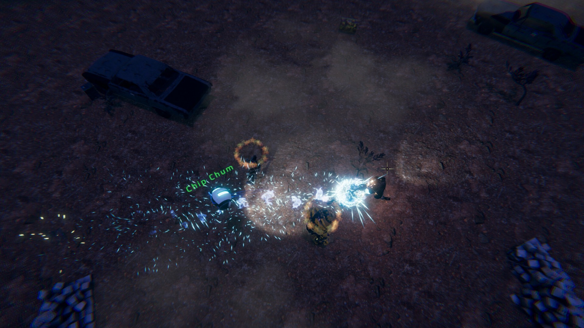 The image depicts a nighttime scene set on a rough, barren terrain with scattered debris and two abandoned vehicles visible at the edges. In the center, there is an intense confrontation where a small robot or drone labeled "Chip Chum" emits a bright, sparkling beam or energy blast toward a humanoid figure. Two other humanoid figures nearby appear to be engulfed in fiery rings, suggesting combat or an attack in progress. The overall atmosphere is dark and chaotic, illuminated primarily by the glowing effects of the energy and fire.